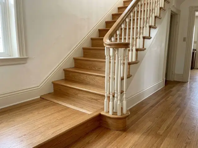 Oak staircase with turned balusters meeting an oak hardwood floor