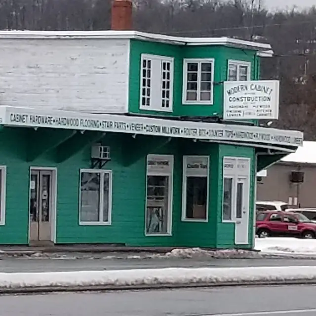 Green two-story Modern Cabinet and Construction store with an awning listing hardware, flooring, stair parts and millwork